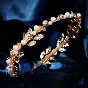Detail shot of golden bridal headband with pearls and crystals on blue silk background