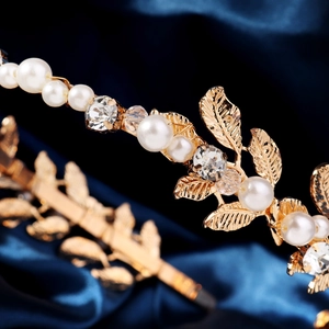Detailed macro view of golden metal leaves and white pearls on an elegant headband