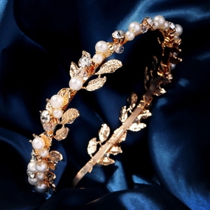 Close-up of golden leaf headband with white pearls and sparkling rhinestones on blue silk