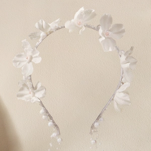 Detailaufnahme weißer Stoffblumen und rosa Perlenakzenten auf einem silbernen Haarband