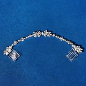 Detail von silbernem Braut-Haarschmuck mit Kristallblumen und Strass auf blauem Stoff
