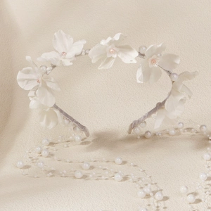 Detail von weißen Stoffblumen und Perlen auf einem Samthaarreif mit hängenden Quasten