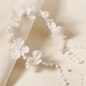 Detailaufnahme von weißem Satin-Blumen-Stirnband mit Perlen und romantischen Quasten