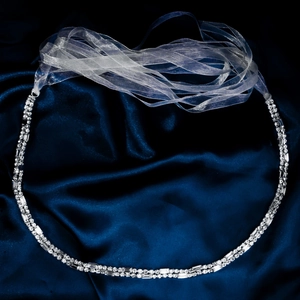 Detailed shot of sparkling rhinestone belt with white satin ribbon on blue silk
