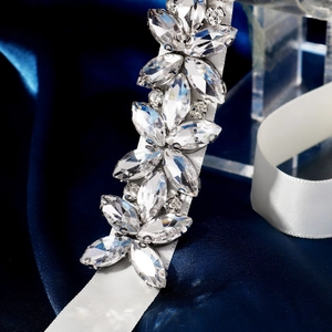 Dettaglio del motivo floreale con strass su cintura da sposa in raso bianco per abiti