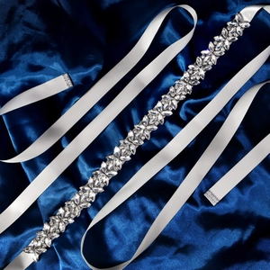 Dettaglio macro della cintura da sposa con foglie di cristallo e strass su seta blu scuro