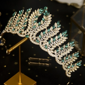 Close-up of golden crown with emerald and white crystals on laurel leaf design