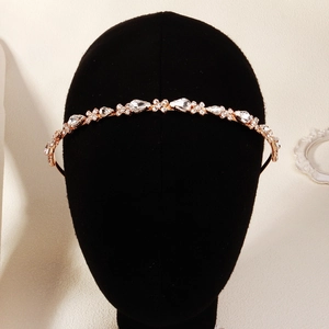 Détail du serre-tête doré avec strass transparents sur un support en velours noir