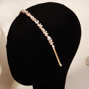 Détail d'un serre-tête floral doré orné de strass sur un présentoir en velours