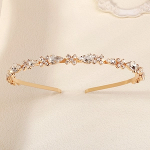 Détail d'un serre-tête doré avec cristaux en goutte et fleurs en strass sur velours