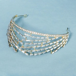Macro view of luxurious gold bridal crown with cascading crystal diamonds on blue surface