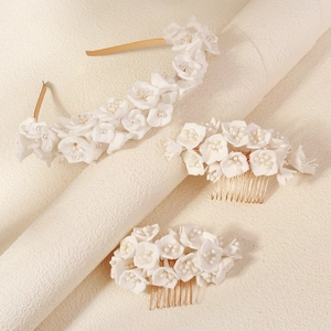 Detail view of bridal hair set featuring white fabric flowers and golden rhinestones