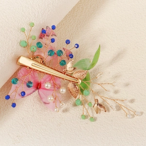 Detail of golden butterfly hair clip with pink gradient fabric and pearl beads