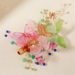 Detail of colorful butterfly hair clip with faux pearls and golden alligator base