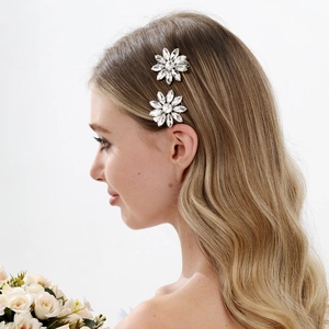 Detailopname van twee zilveren bloem haarspelden met heldere strassteentjes op blond haar