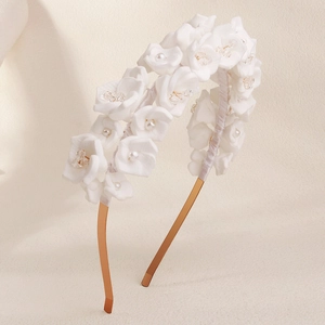 Detailed macro view of white floral bridal headband with faux pearls and beads