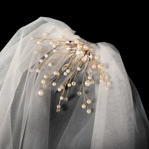 Détail d'un peigne à cheveux de mariée doré avec perles blanches et cristaux brillants