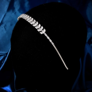 Détail d'un serre-tête argenté avec zircons en forme de feuilles sur fond de soie sombre