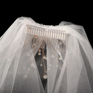Détail du voile de mariée blanc avec perles délicates fixé sur un peigne en métal argenté