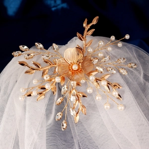 Détail du peigne de mariée doré avec perles et cristaux sur un voile en maille douce