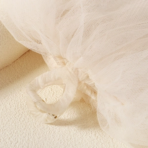 Détail macro de la texture du voile de mariée en tulle ivoire avec anneau en résine