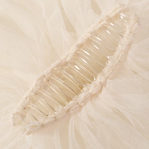 Détail macro du tulle plissé ivoire et du peigne en plastique pour accessoire de voile mariée