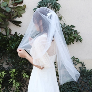 Détail d'un voile de mariée blanc à double couche avec nœud et robe de mariée à paillettes