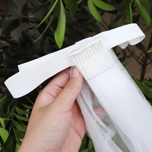 Détail d'un voile de mariée blanc avec nœud en satin et peigne à cheveux argenté