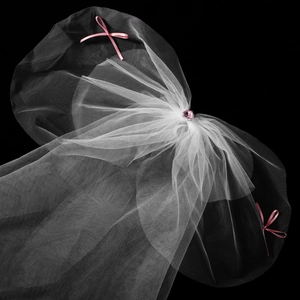 Détail d'un voile de mariée en résille blanche avec cristal coeur rose et noeuds