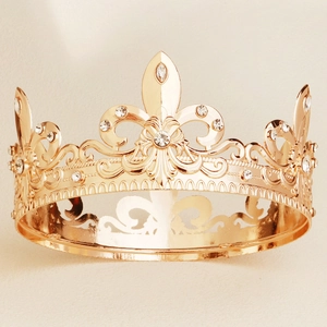 Detailed close-up of golden Baroque crown featuring fleur-de-lis motifs and sparkling rhinestones