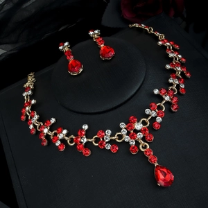 Détails d'une parure de bijoux de mariée dorée avec pierres rouges en poire et cristaux