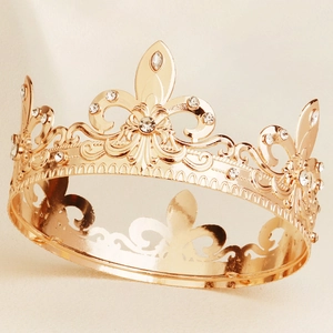 Detailed macro view of golden baroque crown with fleur-de-lis and sparkling rhinestones