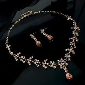 Parure de bijoux de mariée luxe or rose avec cristaux champagne sur fond en soie noire