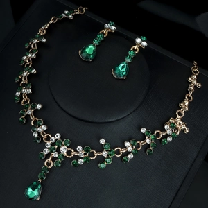 Détails du collier émeraude et des boucles d'oreilles pendantes en or avec cristaux