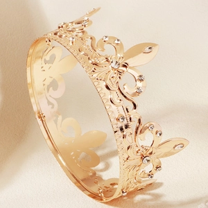 Close-up of golden baroque crown with intricate floral reliefs and white rhinestones