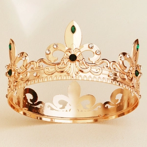 Detail of vintage gold crown featuring green gemstones and fleur-de-lis engravings