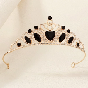 Detail of a golden crown featuring a black heart-shaped gem and sparkling white crystals