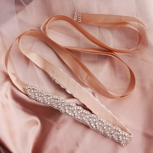 Dettaglio della cintura da sposa con strass scintillanti su nastro di raso champagne