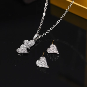 Macro detail of silver heart necklace and stud earrings set with sparkling cubic zirconia