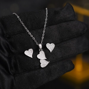Close-up of sparkling heart-shaped necklace and earring set with white zircons