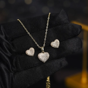 Detailed view of heart-shaped zircon necklace and earrings set held with black silk gloves