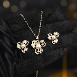 Macro view of gold jewelry set with zircon petals and pearls on a black glove