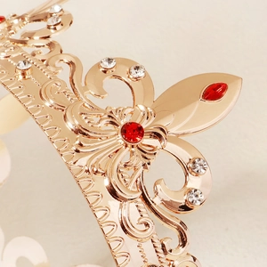 Macro shot of gold Baroque crown showing intricate filigree and red gemstone settings