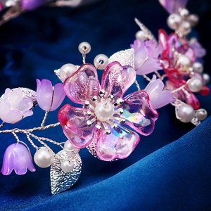 Nahaufnahme von rosa Harzblüten und weißen Perlen auf einem silbernen Braut-Haarband