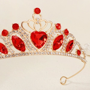 Macro side view of golden heart crown featuring large red gemstones and white rhinestones