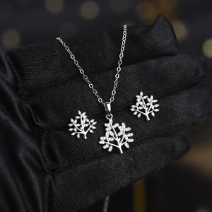 Detailed view of silver Tree of Life necklace and earrings set with cubic zirconia