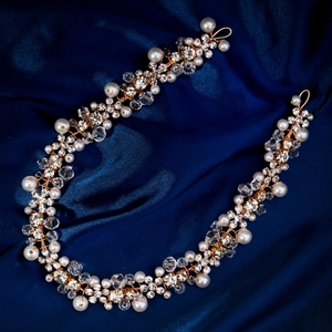 Elegant gold bridal hair vine with white pearls and crystal beads on silk background