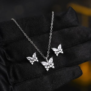 Detailed view of silver butterfly necklace and earrings set with sparkling zircon stones