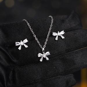 Elegant silver bow jewelry set with sparkling zircon necklace and earrings on black gloves