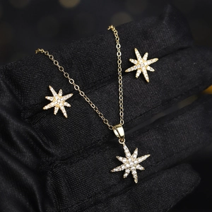 Macro detail of gold starburst jewelry set with sparkling zircons held in black gloved hand